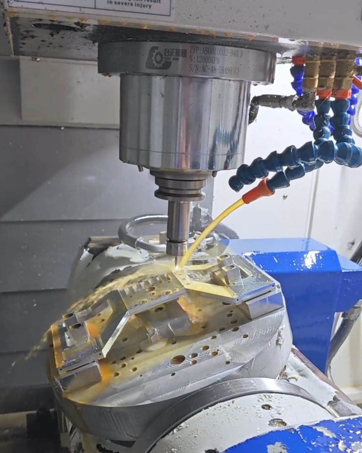 CNC spindle machining a metal workpiece with coolant flowing over the cutting area